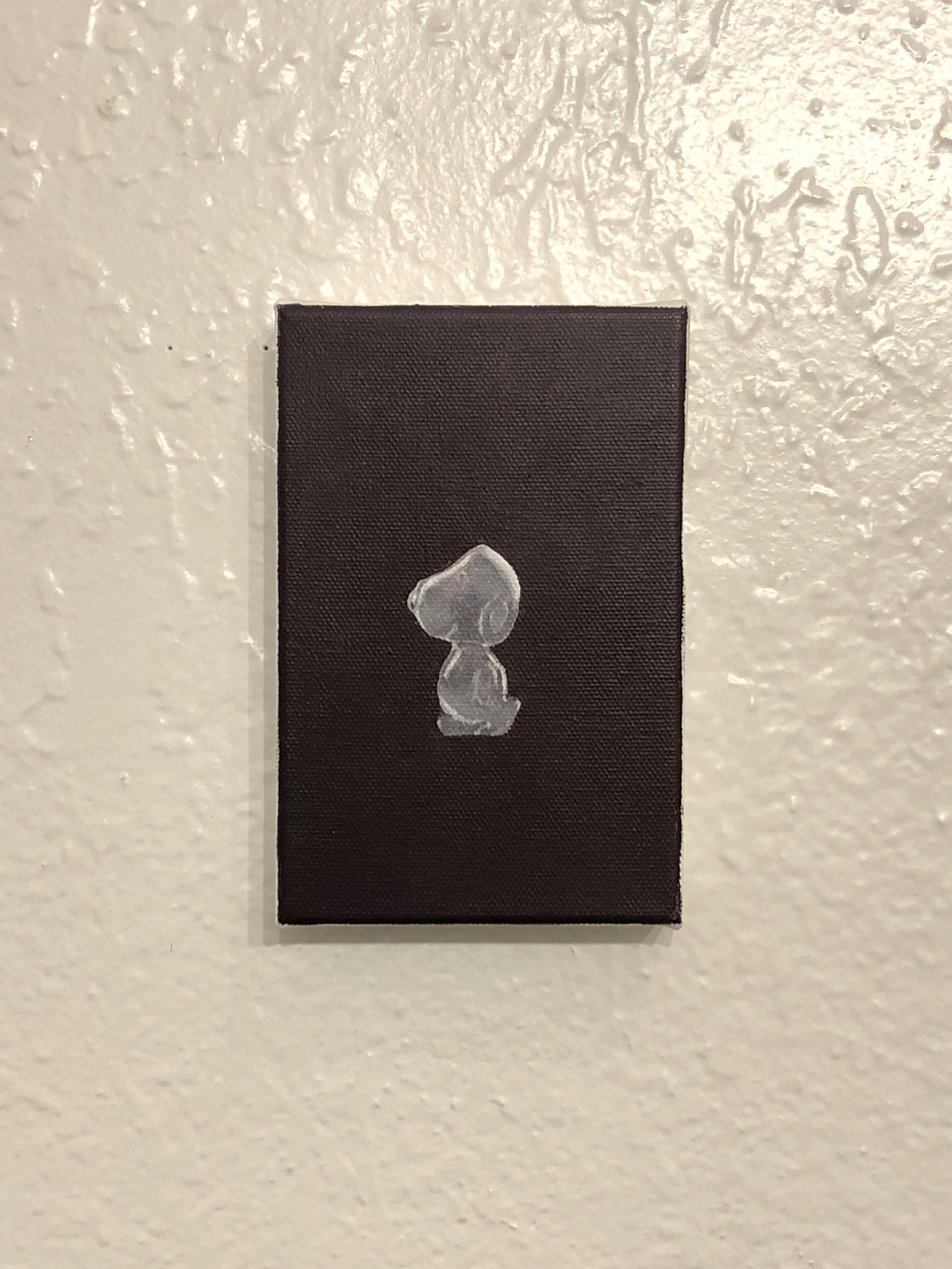 Detail of a painting of snoopy the dog made of stone hung on a white wall